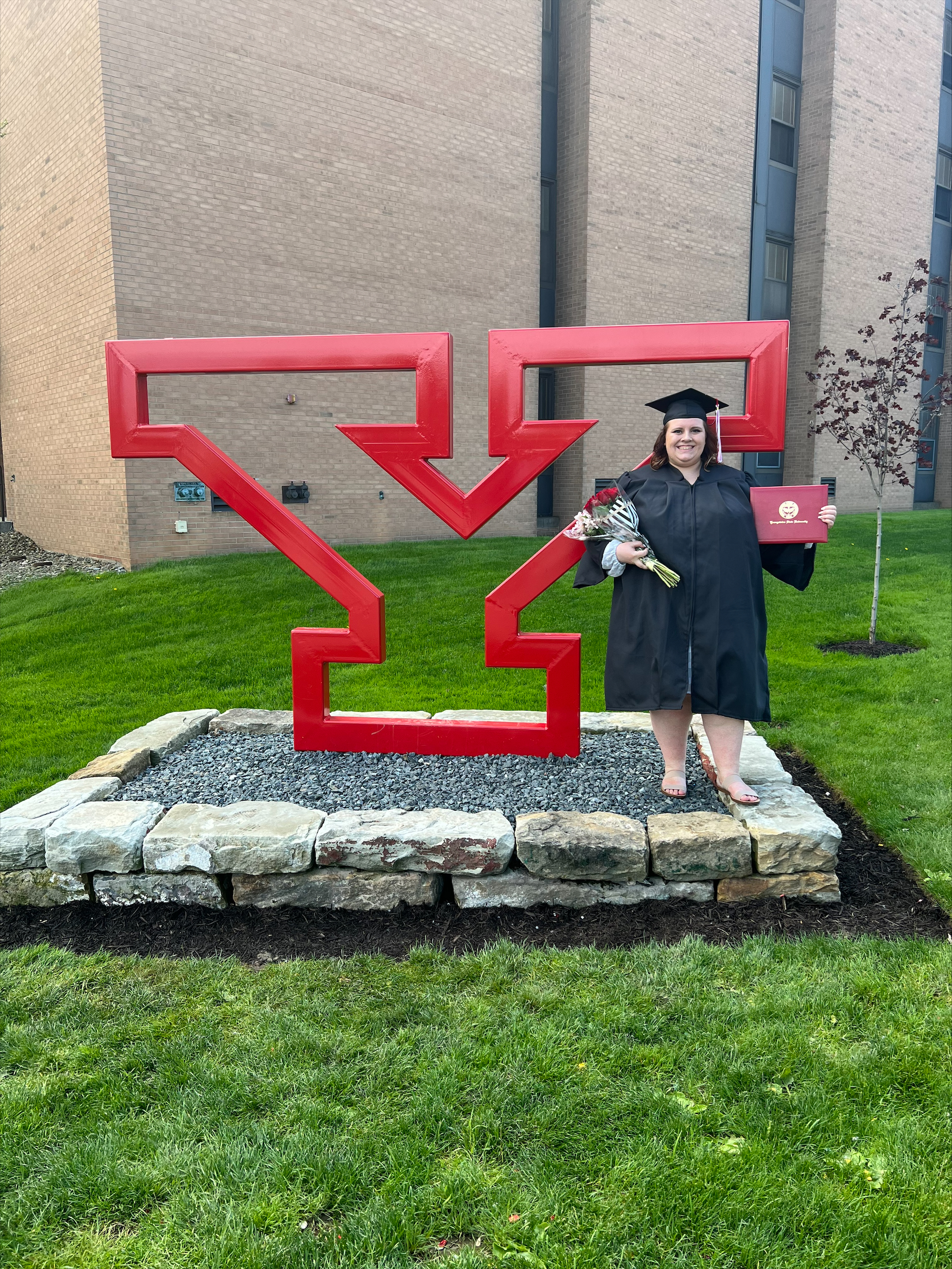 Nicole Zimmerman poses in her graduation cap and gown on campus