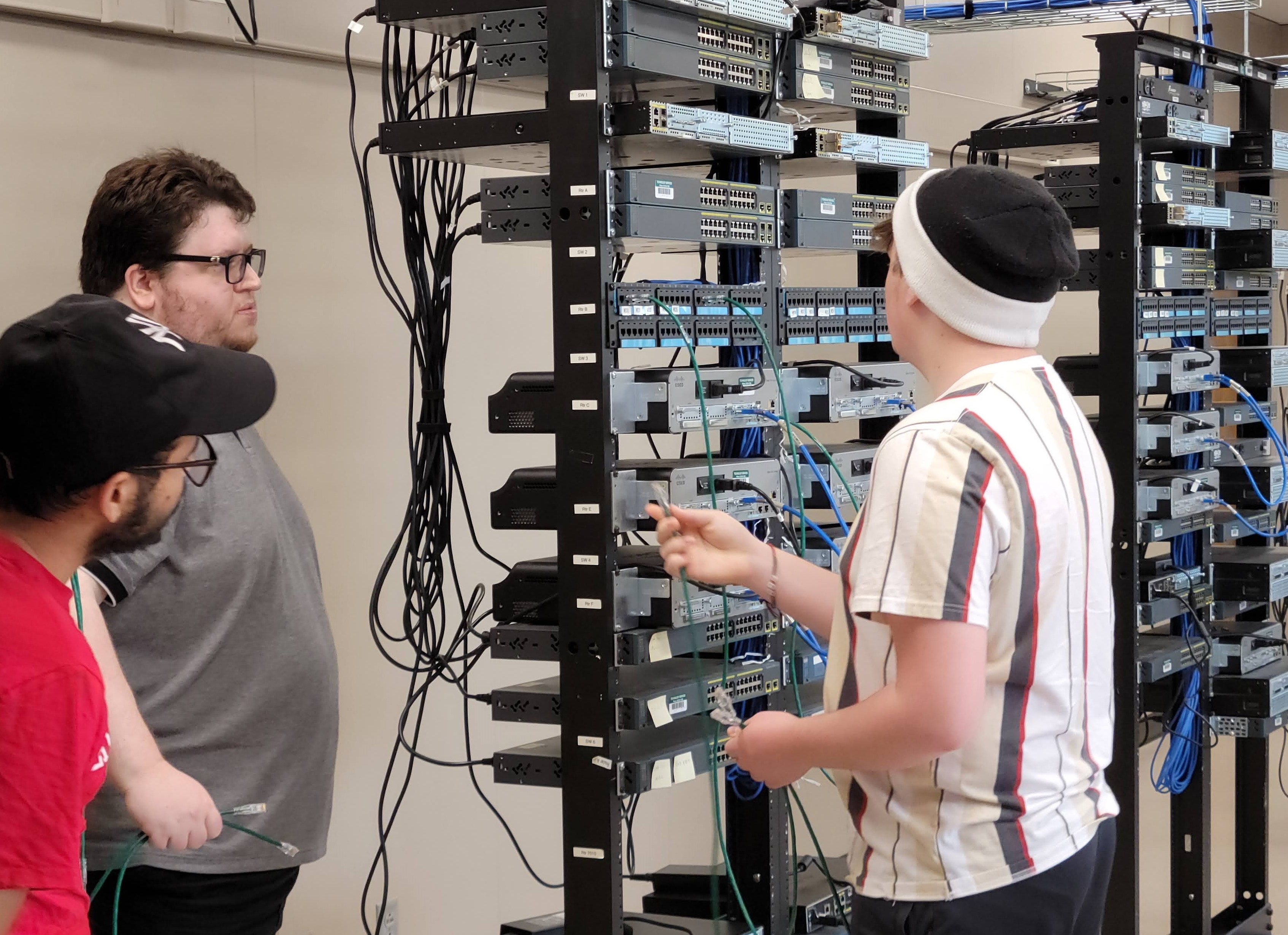 A student connects network cables at a technology day workshop