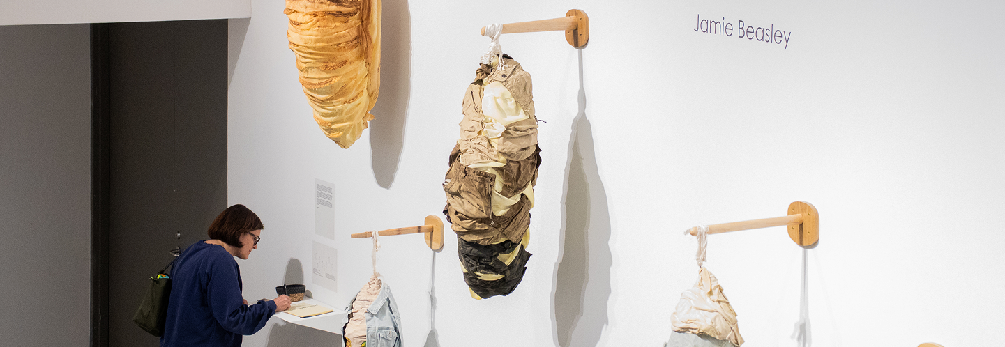 BFA student Jamie Beasley's senior exhibition on display in the McDonough Museum. The work is large-scale sculptures of cocoon-like pods constructed of clothing. A variety of textures and colors are used.