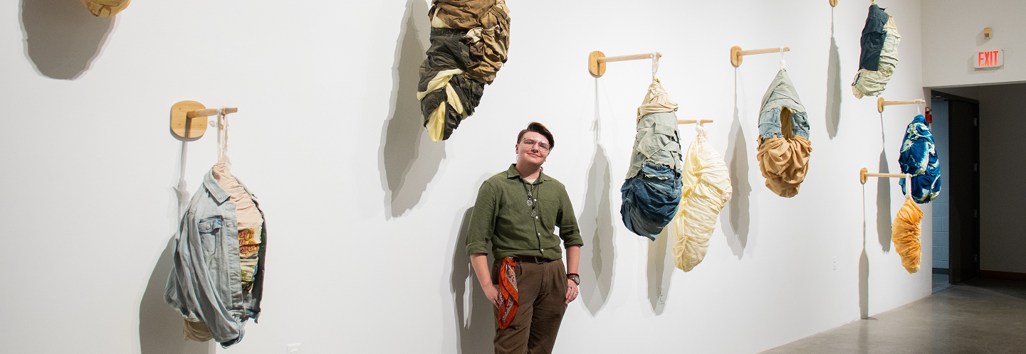 BFA student Jamie Beasley's senior exhibition on display in the McDonough Museum. The work is large-scale sculptures of cocoon-like pods constructed of clothing. A variety of textures and colors are used.